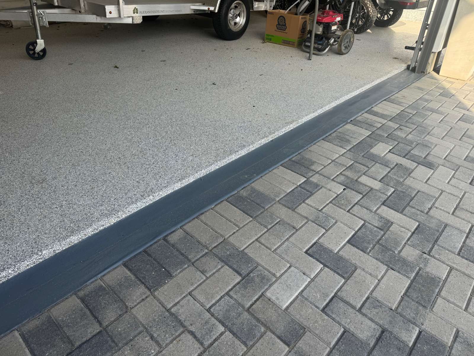 Flake-coated garage floor meeting a paver driveway at the garage door threshold
