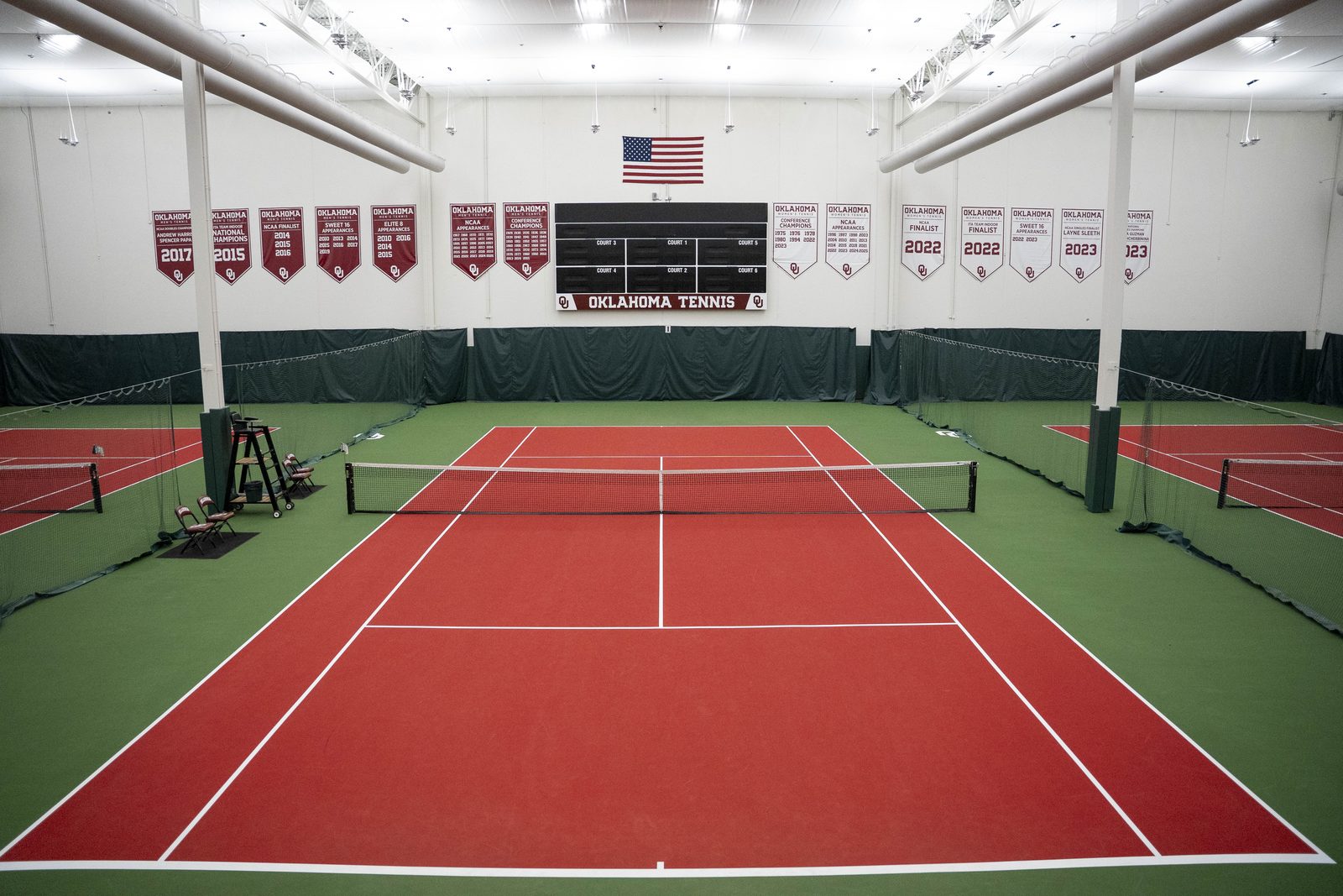Indoor tennis court at the University of Oklahoma with red playing area and green surround