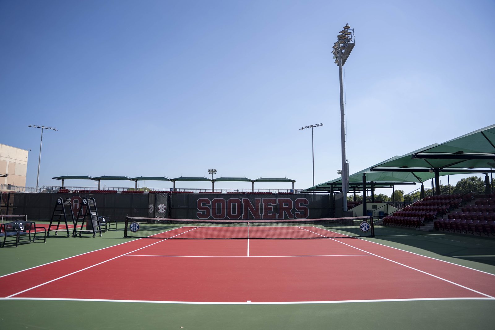 Outdoor tennis court with light poles and shade structures at OU Headington
